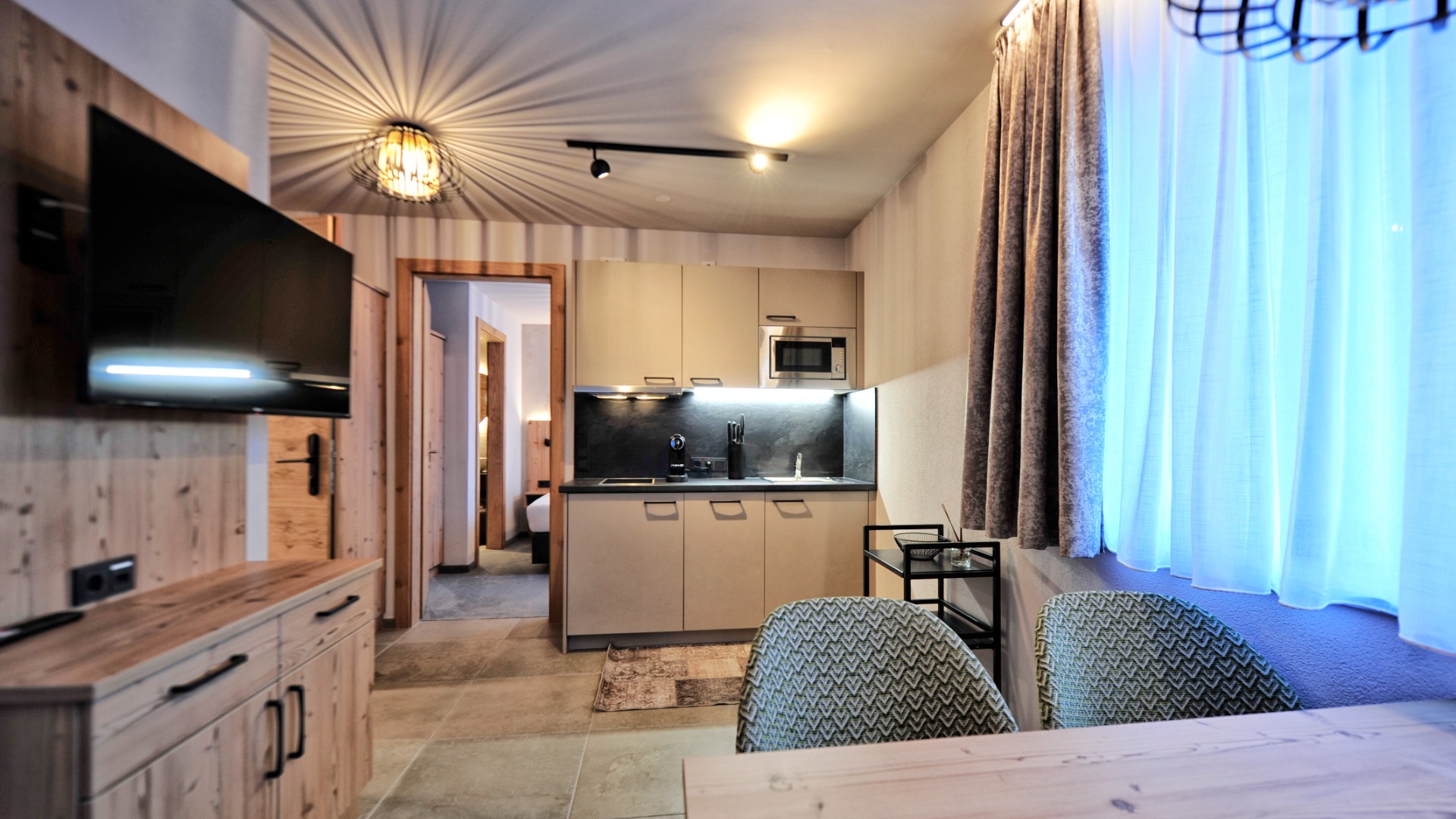 Studio mit Küchenzeile, Esstisch, TV und Blick ins Schlafzimmer – modern und gemütlich eingerichtet.